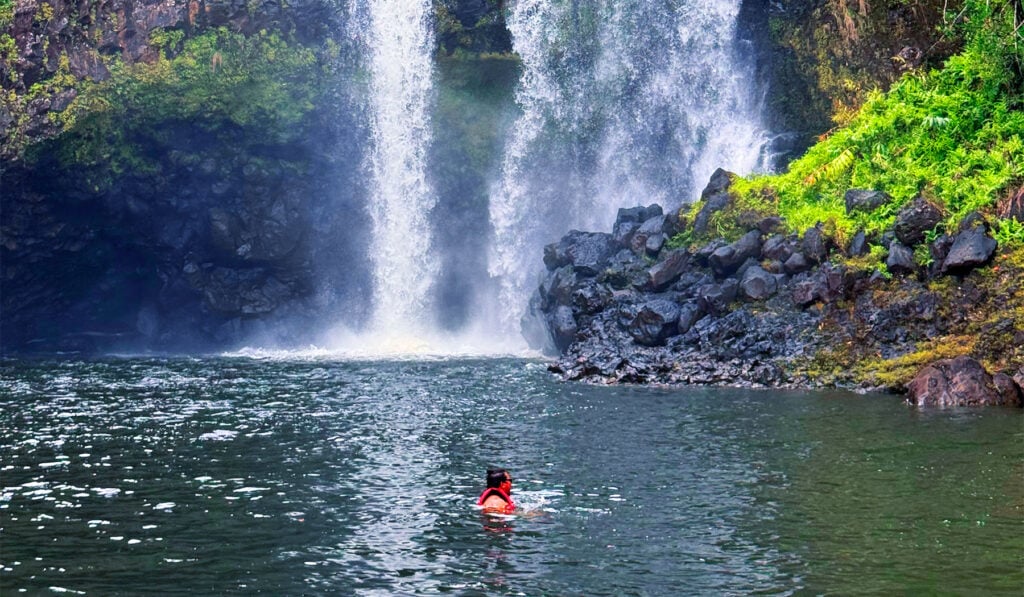 A swimmer in the pool beneath a private multi-tiered waterfall on the Big Island